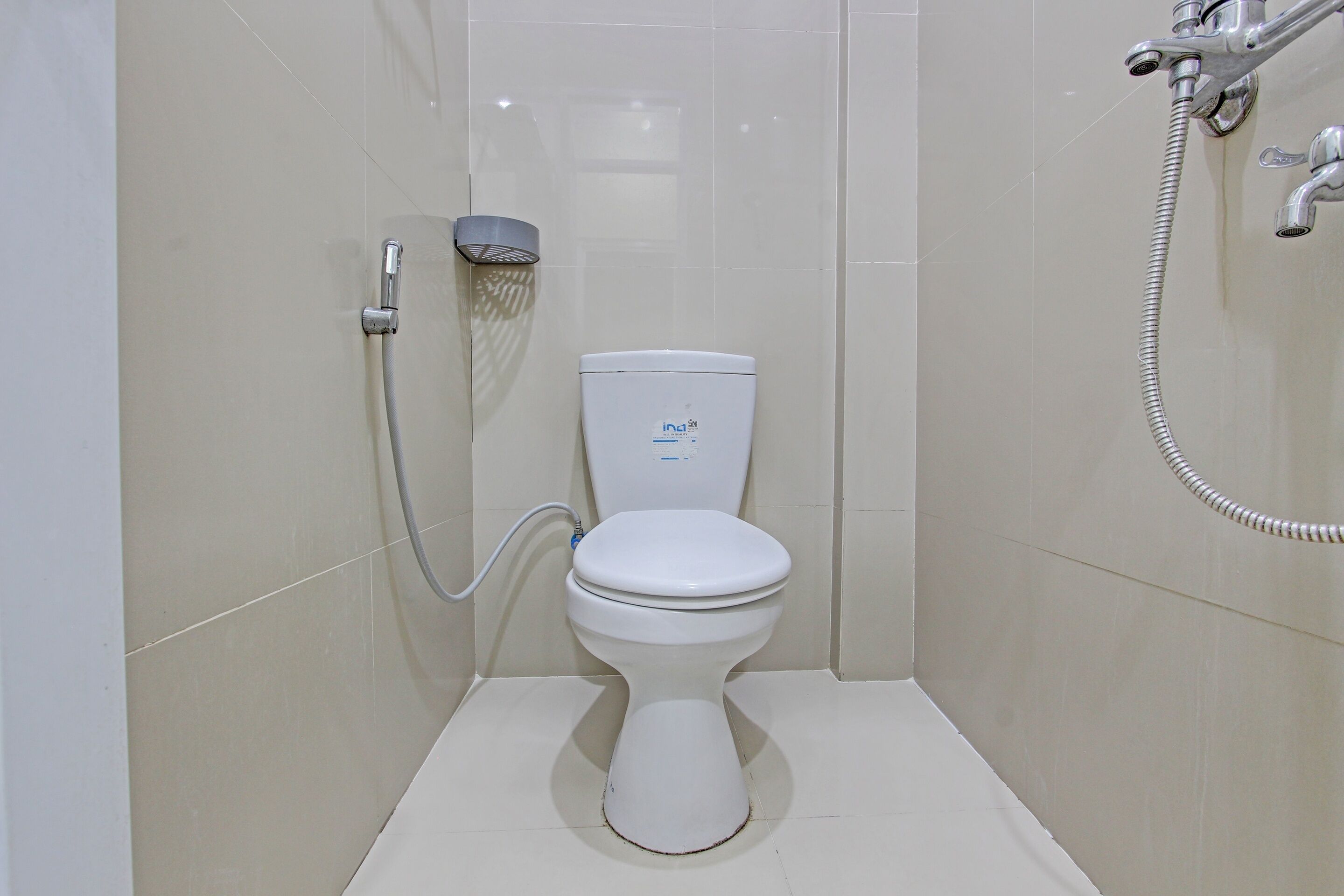 Un baño moderno con inodoro, cabezal de ducha de mano y grifo empotrado.