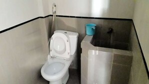 Une salle de bain avec des toilettes blanches, une tasse bleue et un lavabo.