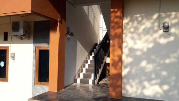 Un escalier menant au deuxième étage, avec une porte et un appareil de climatisation au premier étage.