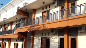 Un immeuble à plusieurs étages, doté de balcons, de climatiseurs et présentant une variété de styles de portes et de fenêtres.