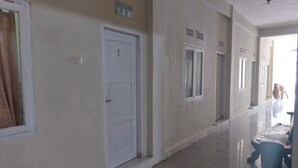 A hallway with white doors, a tiled floor, and a person walking towards the end. - Hotel O Onong's Homestay Near Dodikjur Rindam XIII/Merdeka (Tomohon)