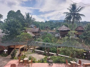 A rustic outdoor area with thatched-roof huts, a patio with wooden furniture, and lush greenery. - Hotel O Onong's Homestay Near Dodikjur Rindam XIII/Merdeka (Tomohon)