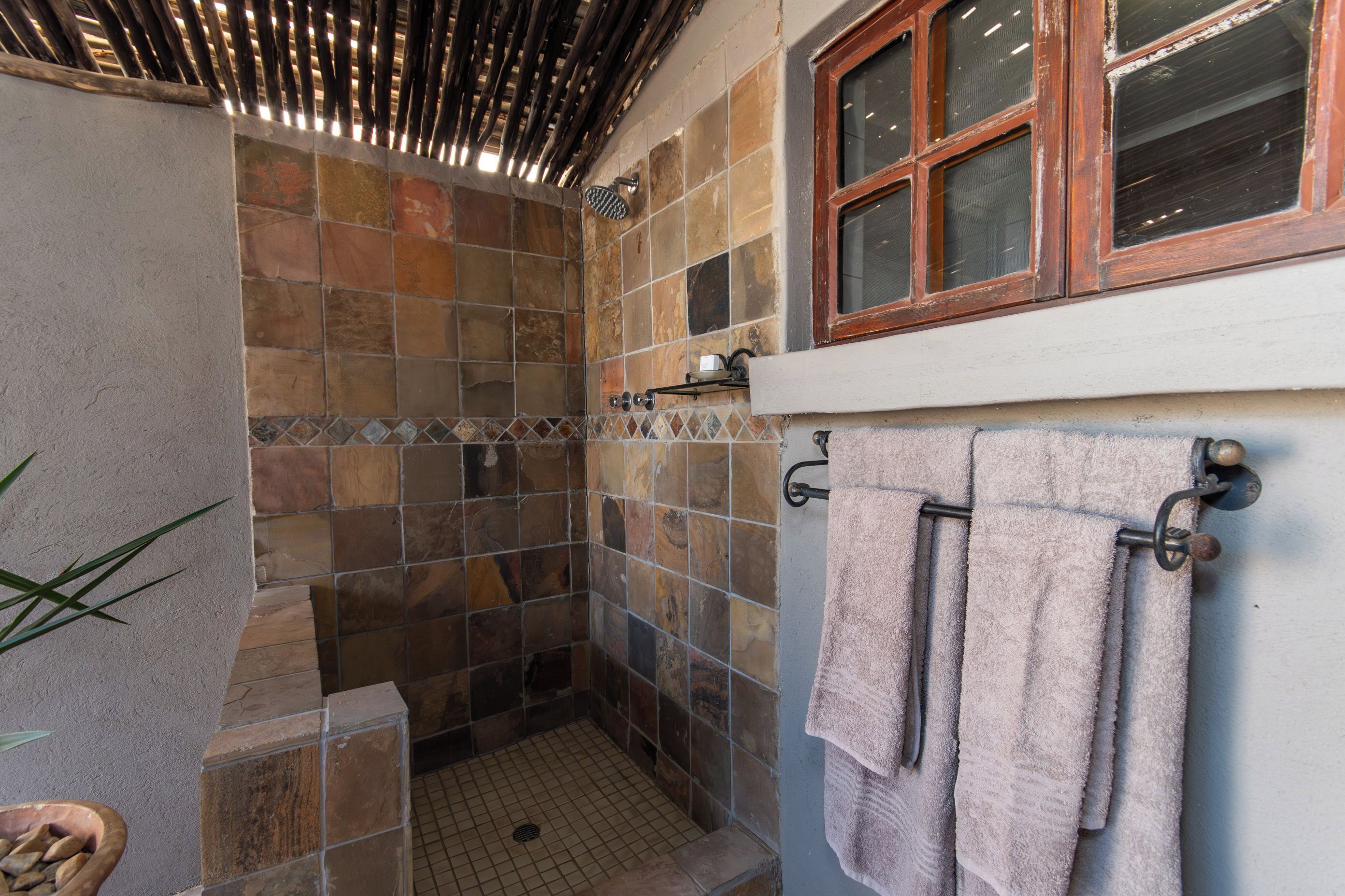 A shower area with tiled walls and a window above.