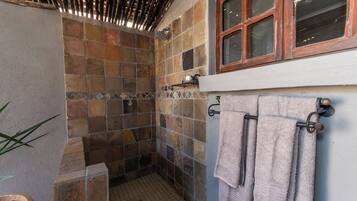 Zona de ducha con paredes de azulejos y una ventana en la parte superior.