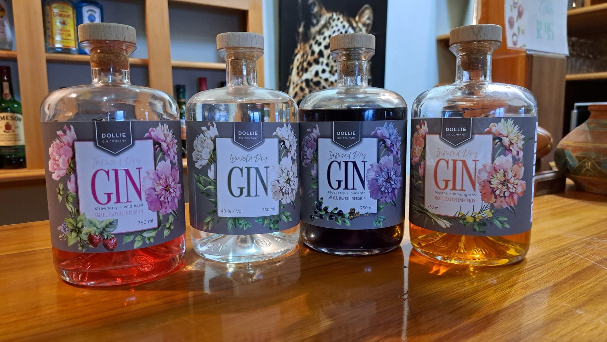 Four bottles of gin with different labels and colors on a wooden surface.