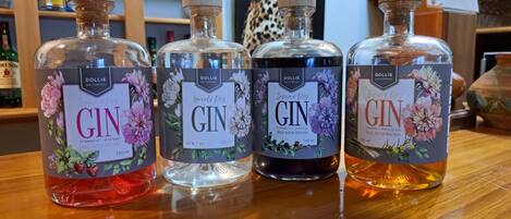 Four bottles of gin with different labels and colors on a wooden surface.