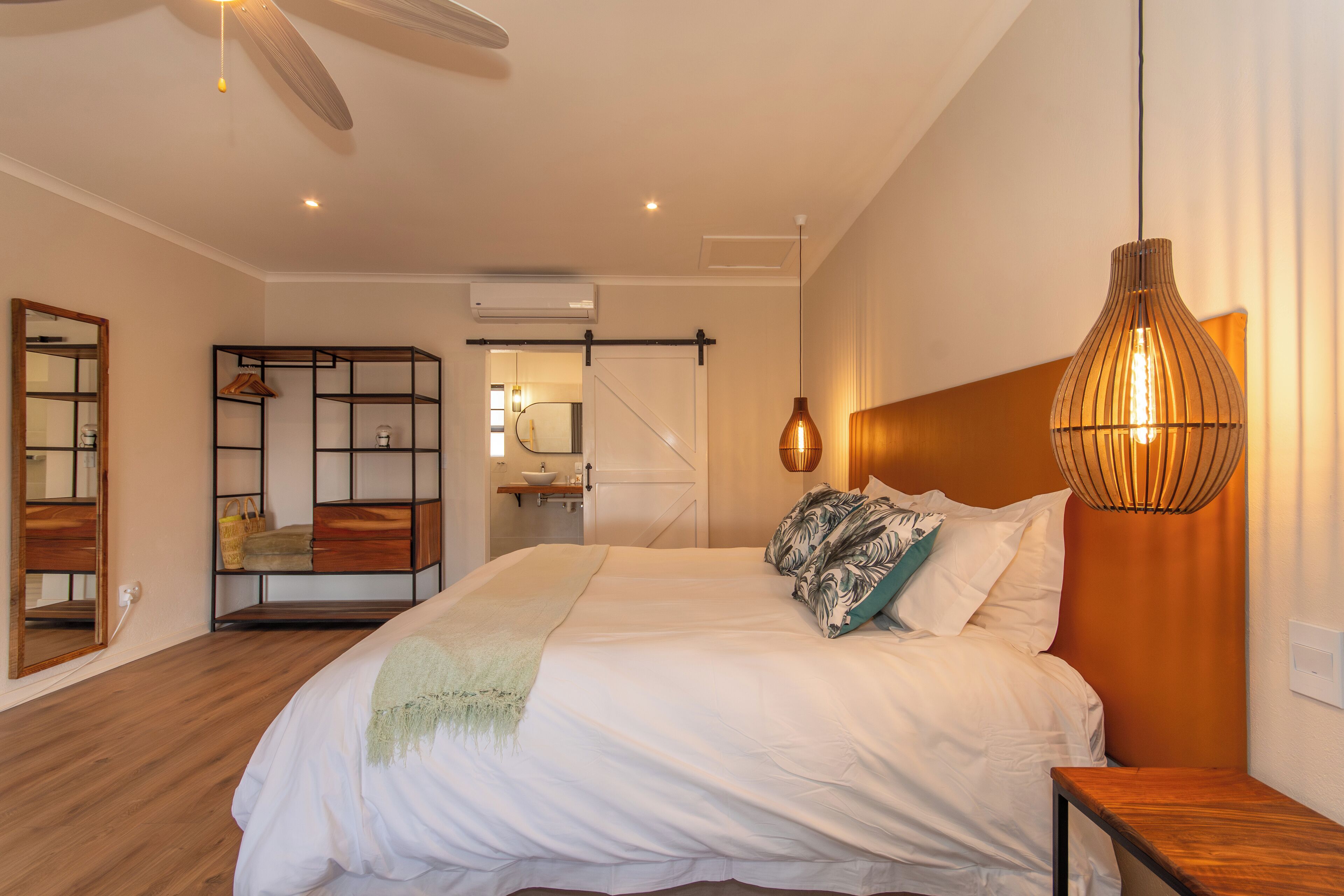 Una camera da letto moderna con un letto grande, una testiera in legno, un lampadario a sospensione e un armadio con specchio.
