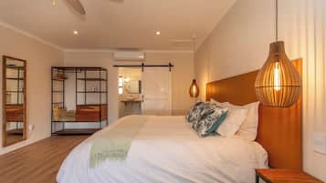 Una camera da letto moderna con un letto grande, una testiera in legno, un lampadario a sospensione e un armadio con specchio.