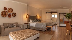 Une chambre moderne avec un lit, des tables de chevet, un canapé et un fauteuil.