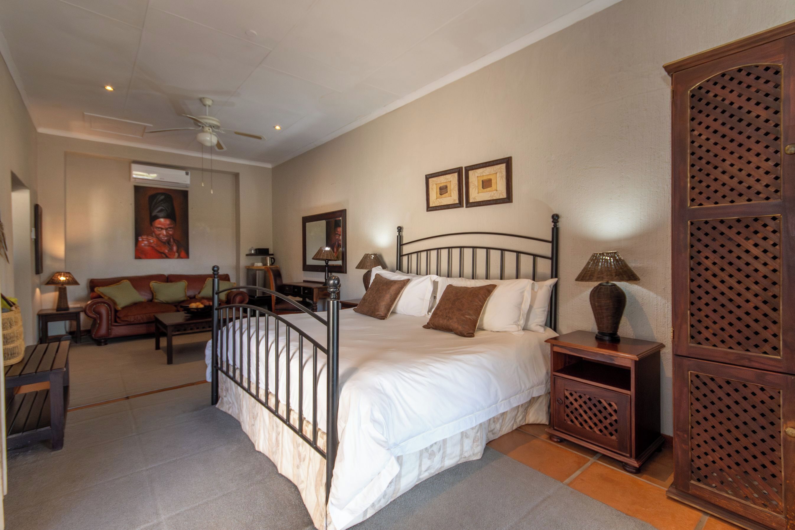 A bedroom with a bed, nightstands, a wooden cabinet, a ceiling fan, a sofa, and a coffee table.