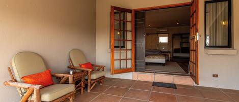 A room with two wooden chairs, a bed, and a window.