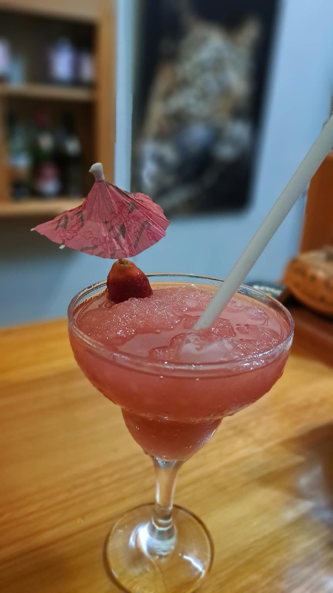 Un cóctel en un vaso con pajita y un paraguas decorativo.