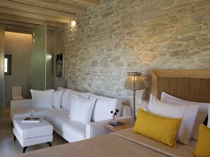 Ein modernes Schlafzimmer mit Steinwand, weißen Möbeln und einem gelben Kissen.