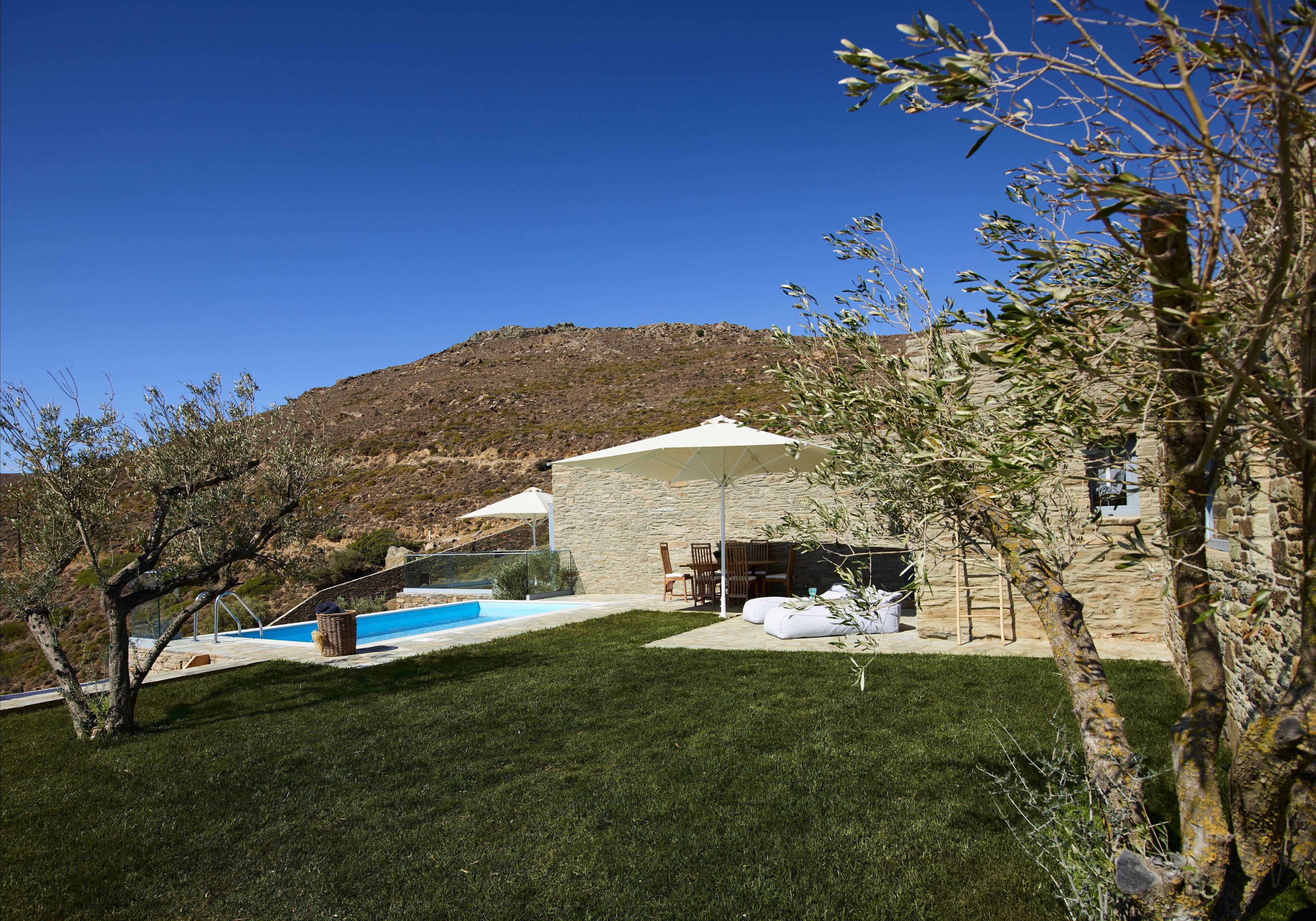 A backyard with a swimming pool, outdoor furniture, and a stone building.