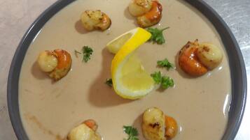 A bowl of creamy soup with seared scallops and lemon garnish.