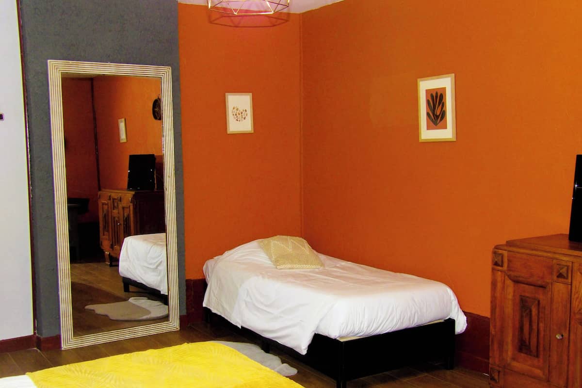 Une chambre à coucher comprenant un lit, un miroir, une commode et un mur orné de deux tableaux encadrés.