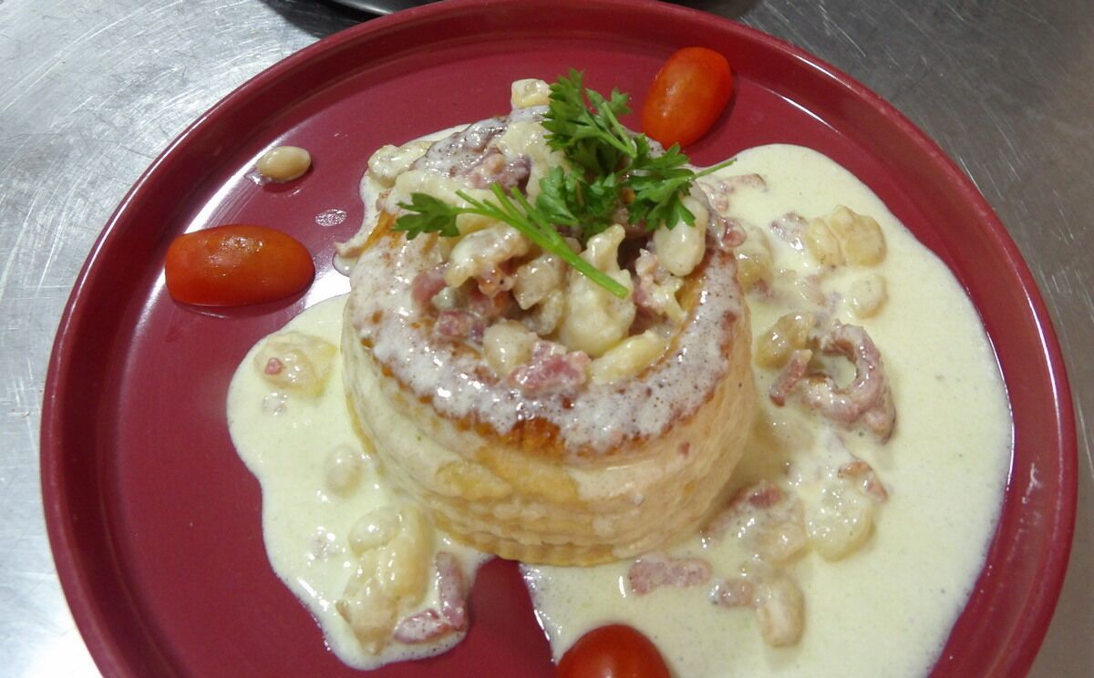 A dish with a creamy sauce, garnished with parsley, served on a red plate.