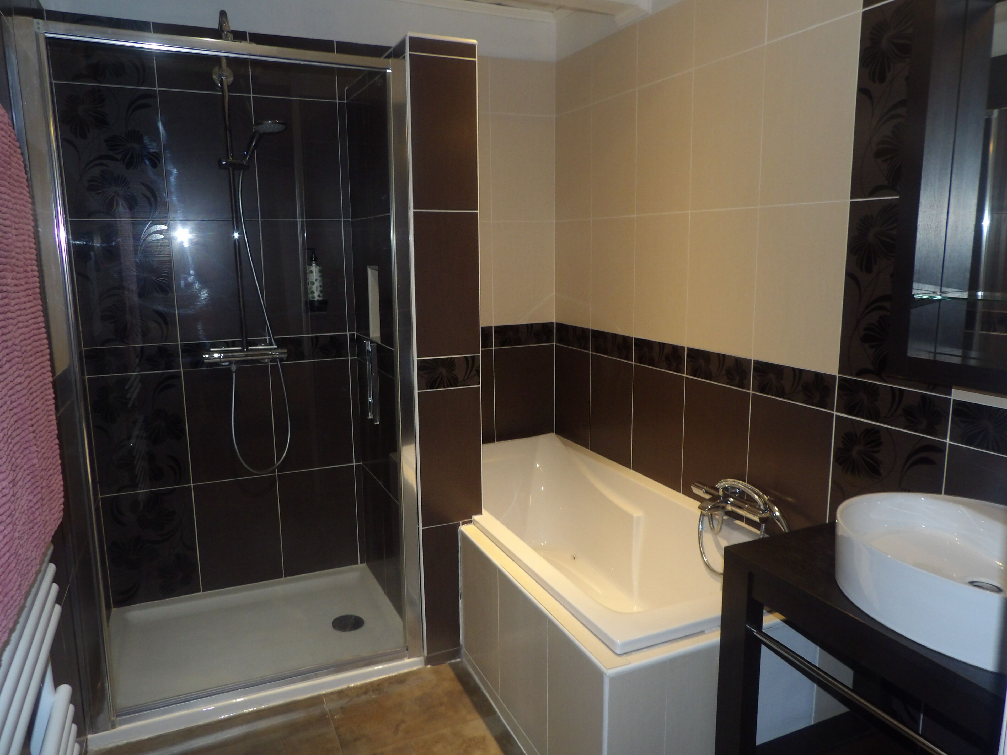 A bathroom with a glass-enclosed shower, a white bathtub, and a sink.
