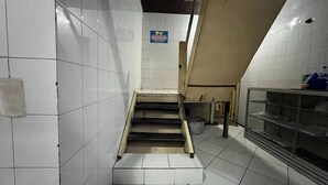 A staircase in a public building with white tiled walls and a blue sign above it. - OYO 92675 Hotel Rosna (Makassar)