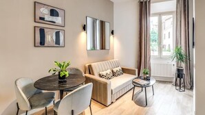 Un salon moderne avec un canapé, deux fauteuils, une table ronde et des œuvres d’art accrochées aux murs.
