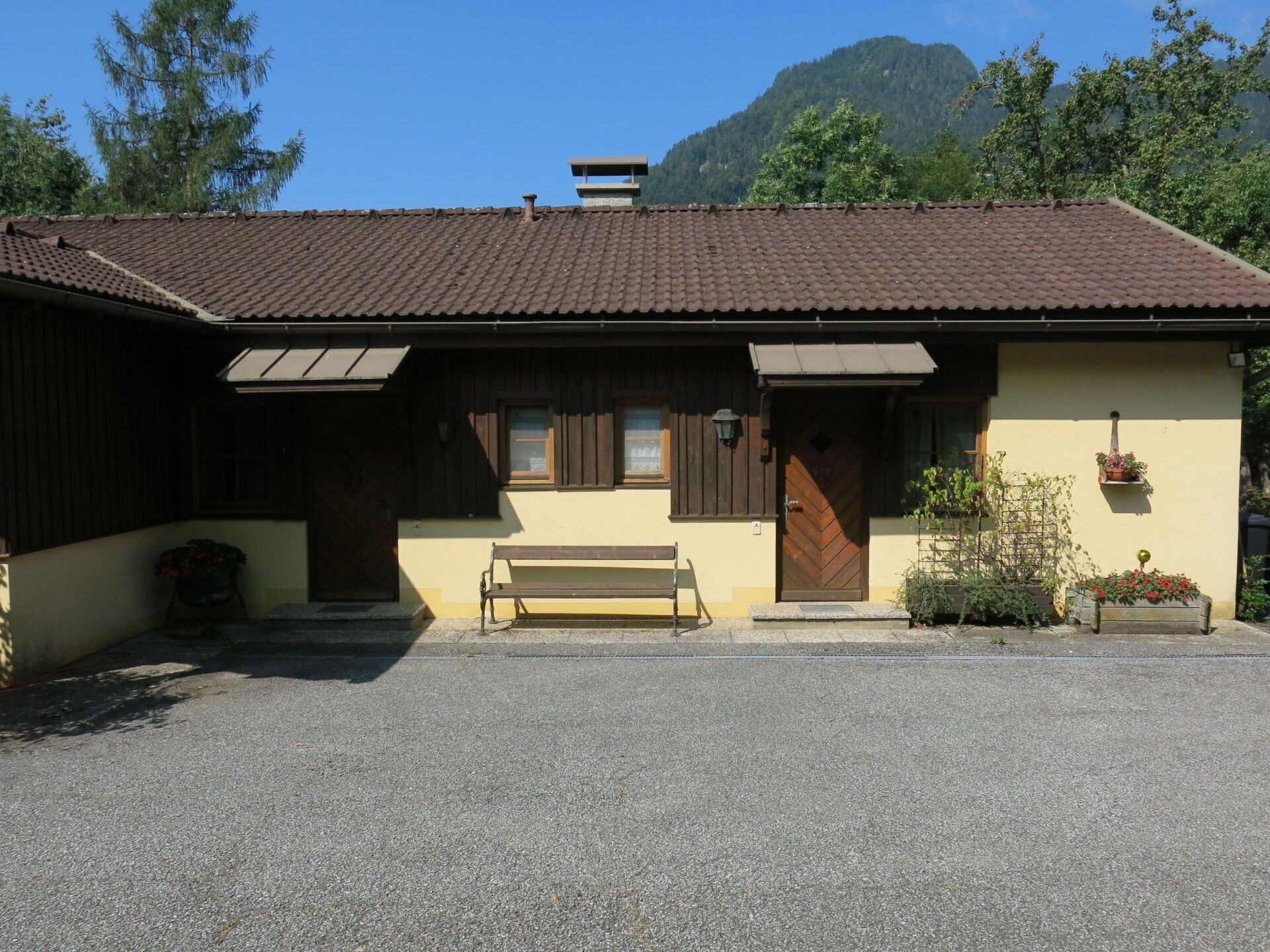 A traditional chalet with a sloped roof, wooden shutters, and a bench in front.