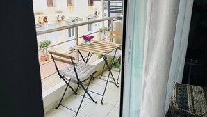 A balcony with a wooden table, a cushioned chair, and a small potted plant. - Cozy Nest - 2min To Beach, 6min Walk To (Chania)
