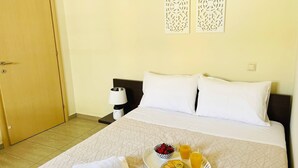 A hotel room with a bed, a tray with breakfast items, a lamp, and decorative wall art. - Cozy Nest - 2min To Beach, 6min Walk To (Chania)