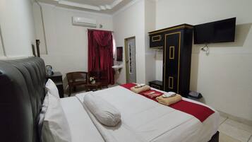 Hotelkamer met een bed, bureau, stoel, kledingkast, televisie en een airconditioning.