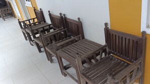 Wooden chairs lined up against a yellow wall with a window. - Hotel O Wisma Parakita Syariah Near RS Faisal Patalasang (Pattallassang)