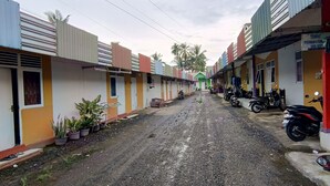 A narrow street lined with colorful buildings, some with visible doors and windows, and a few potted plants along the sides. - Hotel O Wisma Parakita Syariah Near RS Faisal Patalasang (Pattallassang)