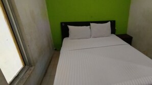 A small, single-bed room with a green wall and a white bedspread. - Hotel O Wisma Parakita Syariah Near RS Faisal Patalasang (Pattallassang)