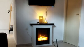 Un saló amb una xemeneia, un televisor de pantalla plana penjat per sobre i una catifa amb dibuixos al terra.