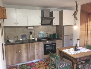 A kitchen with wooden cabinets, a stove, a sink, and a dining table with chairs.