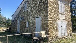 A stone building with two white doors and a small window. - Petite Maison Avec Terrain Entre Route, Vignes et Lavande (Sainte-Cécile-les-Vignes)