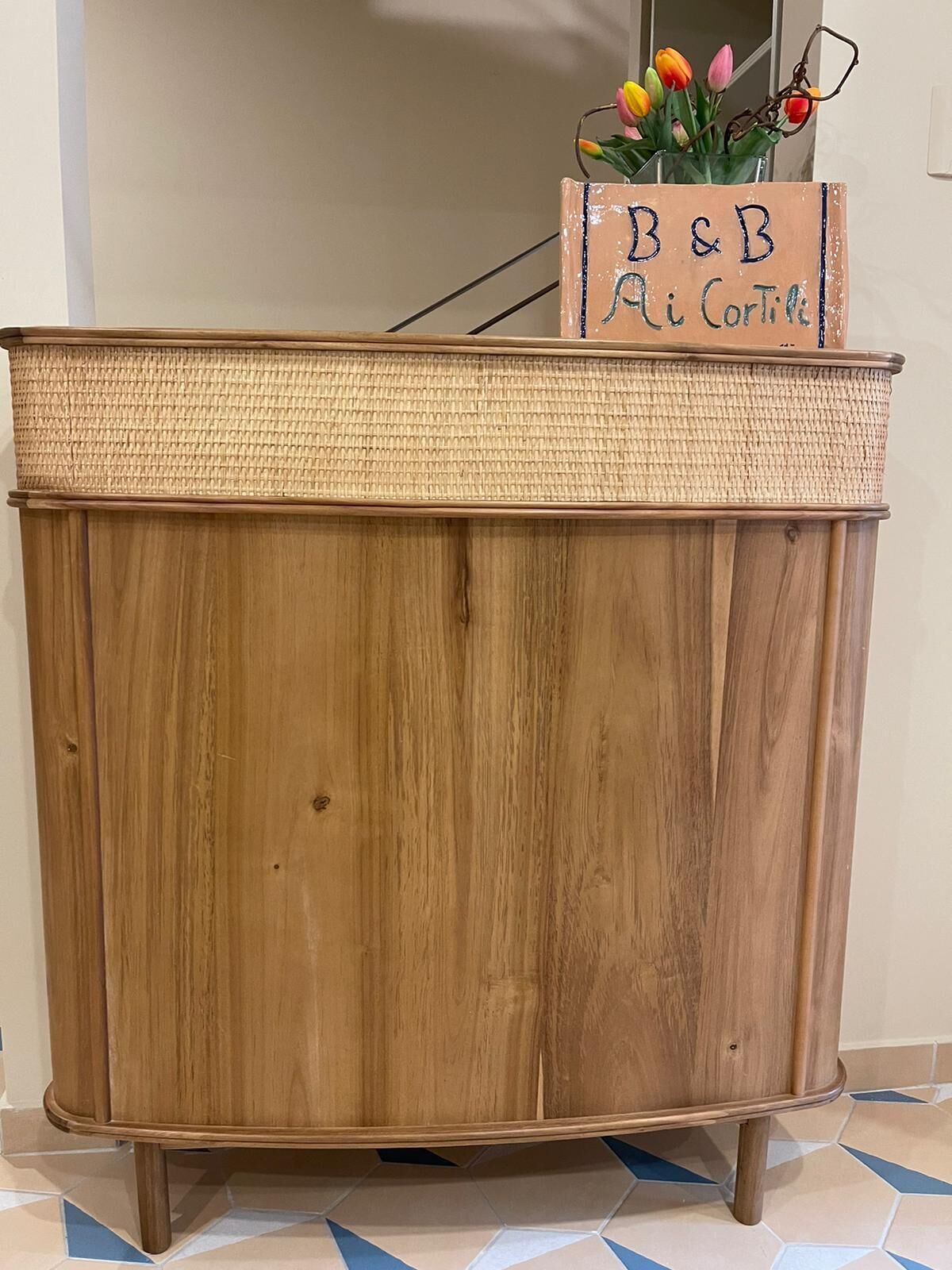 Un mueble de madera con una parte superior trenzada y un letrero en la parte superior que dice "B&B Ai Corti".