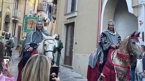 A narrow street with buildings on either side, a person on horseback, and several people taking photos. - Ai Cortili  (Sant'Egidio del Monte Albino)