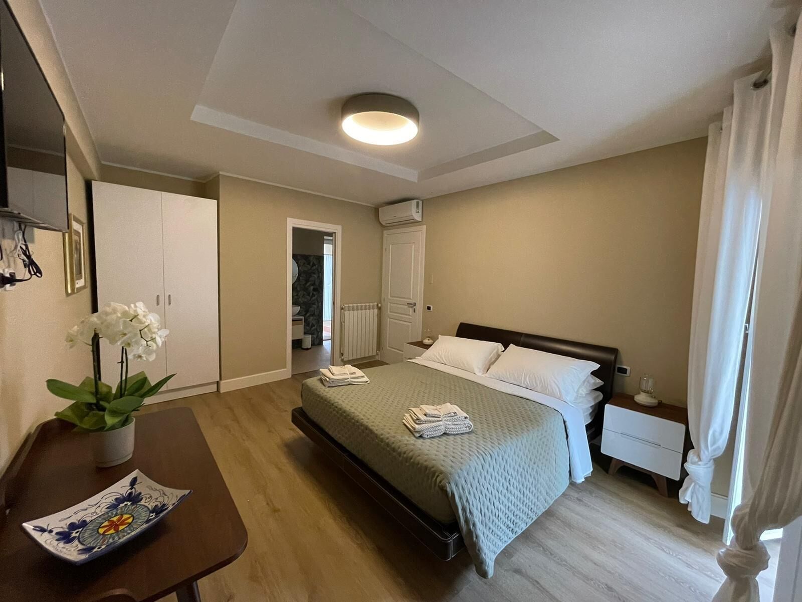 Ein Hotelzimmer mit einem Bett, einem Nachttisch und Blick ins Badezimmer.