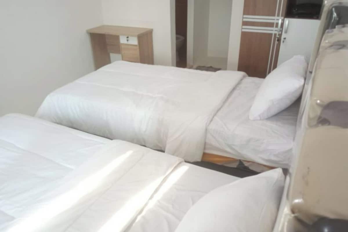 Une chambre d’hôtel avec deux lits, une table de chevet en bois et une armoire.