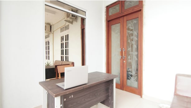 A room with a wooden desk, a laptop, a wooden door with glass panels, and a chair. - Hotel O Bahagia Homestay SyariahNearMonument Park City Sand Pengaraian (Pasir Pengaraian)