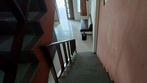 A staircase leading to a room with a brown wall and a window. - Hotel O Wisma Deli Syariah Near RSUD Nene Mallomo Sidenreng Rappang (Pangkajene)
