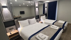 A modern hotel room with two beds, a large mirror, a flat-screen TV, and a wooden nightstand. - Ahg Atlas Hotel Taksim (Istanbul)