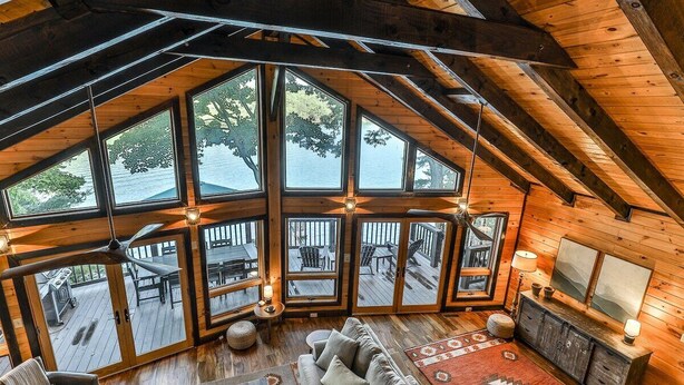 A spacious loft-style room with large windows, a wooden ceiling, and a cozy seating area. - Lakefront Innisfree | Blue Ridge, GA (Blue Ridge)