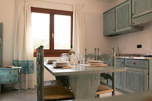 A dining area with a table set for four, a window with curtains, and light-colored cabinetry.