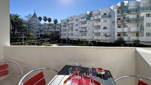 Een balkon met een eettafel, met uitzicht op moderne appartementencomplexen en een heldere lucht.