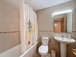 Une salle de bain équipée d’une baignoire, de toilettes, d’un lavabo et d’un miroir.