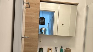 Ein modernes Badezimmer mit einem hölzernen Waschtisch, einem Spiegel und einem weißen Waschbecken.