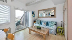 A modern living room with a sofa, a coffee table, and a large mirror. - Unit 1825: 1-Bedroom with Loft | 2nd Floor-Partial Ocean View | Dunes East (Amagansett)