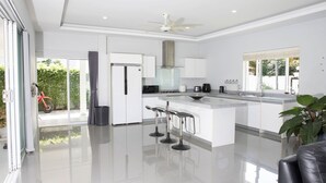 Cozinha moderna com ilha central, banquetas e uma janela ampla.
