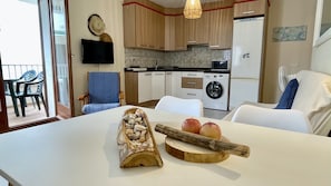 Una cucina moderna con angolo ristoro, lavatrice e televisore a parete.