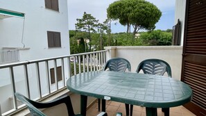 A balcony with a table and chairs, a railing, and a view of trees and buildings. - CALA MONTGO 25 (L'Escala)